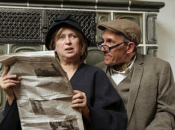Zwei Personen lesen erschrocken eine Zeitung