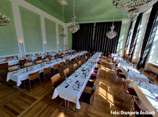 Saal mit grünen Akzenten und festlich gedeckten Tafeln