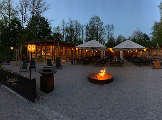 Gastraum von außen bei Dämmerung, Lichter und Feuerschale beim Dinnerkrimi