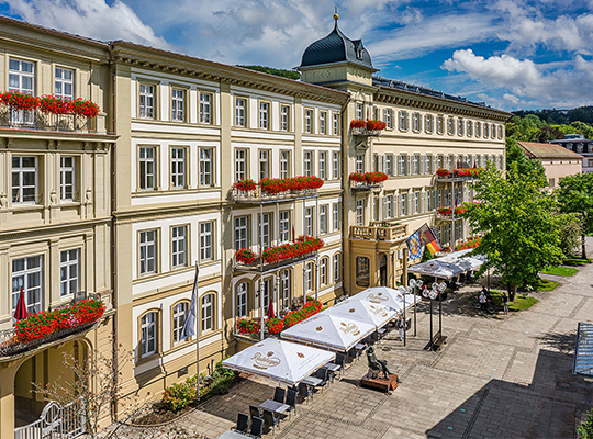 Weiße altertümliche Fassade mit roten Blumen und Marktplatz davor