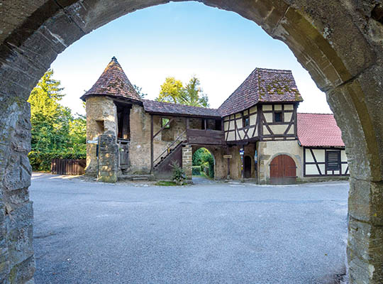 Tagesansicht von einem Steintor auf die Burgruine 