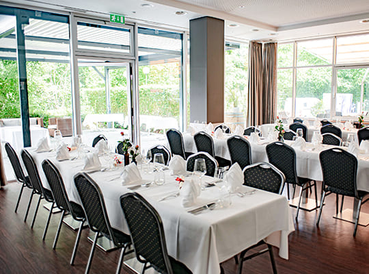 Großer Speisesaal mit riesigen Fensterfronten und langen Tischtafeln angerichtet für das Original Kriminal Dinner