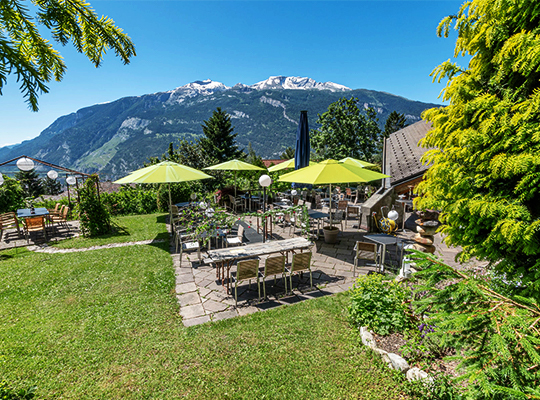 Einsicht auf die Außenanlage und die einladende Terrasse mit wunderschönem Blick auf die Berge