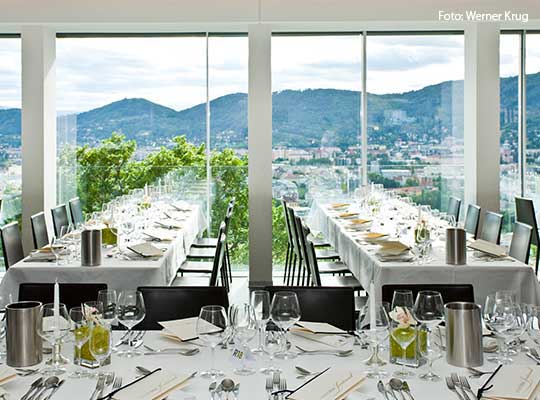 Eingedeckter Saal mit schönem Ausblick auf die Berge im Hintergrund beim Krimidinner Graz