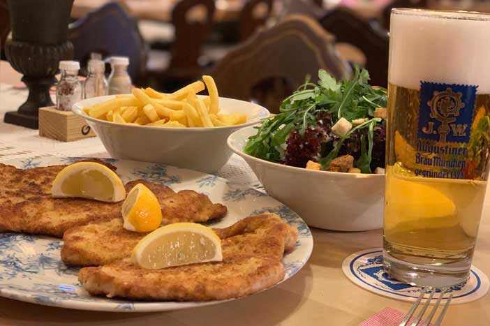 Festlich gedeckter Tisch im Gasthaus Post mit Wiener Schnitzel, Pommes, Salat und Augustiner Bier beim Krimidinner