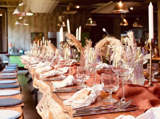 Schön eingedeckter Tisch mit Blumengestecken in angenehmer Beleuchtung