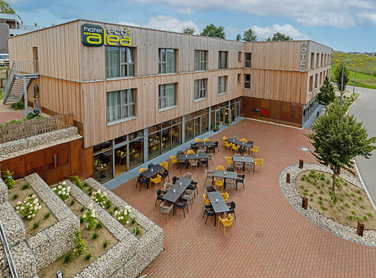 Außenansicht des beeindruckenden Alea Eco Hotels mit schöner Holzfassade und großen Glasfenstern