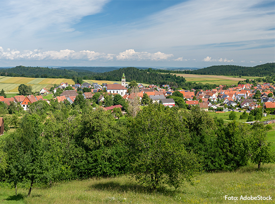 Die Kirche eines kleinen Dorfes ragt mit ihrem Turm über den Bäumen hervor 